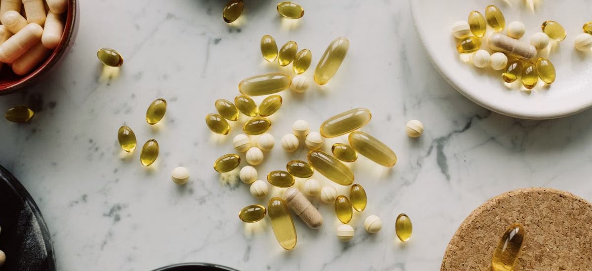 A top view of assorted capsules and pills displayed on a marble surface, showcasing a variety of medicines.